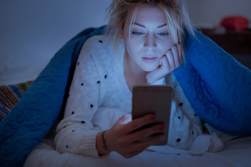 Young woman looking at her phone in bed