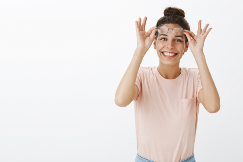woman smiling with her glasses lifted above her eyes