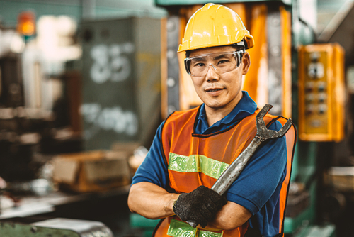 tradesman with a wrench in his hand and wearing a hard hat 