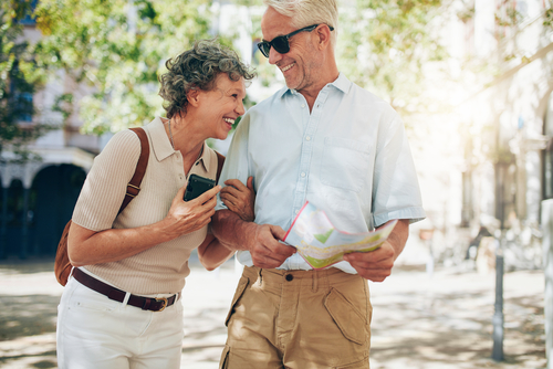 husband and wife walking through park while using map for directions 