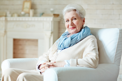 older woman smiling while sitting in chair at home