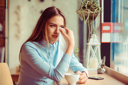 woman at coffee shop wiping her eyes